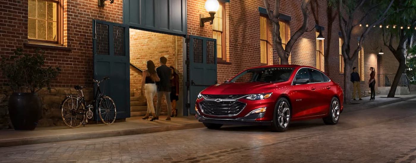 A red 2019 Chevy Malibu RS is shown from the front at an angle on a city street.