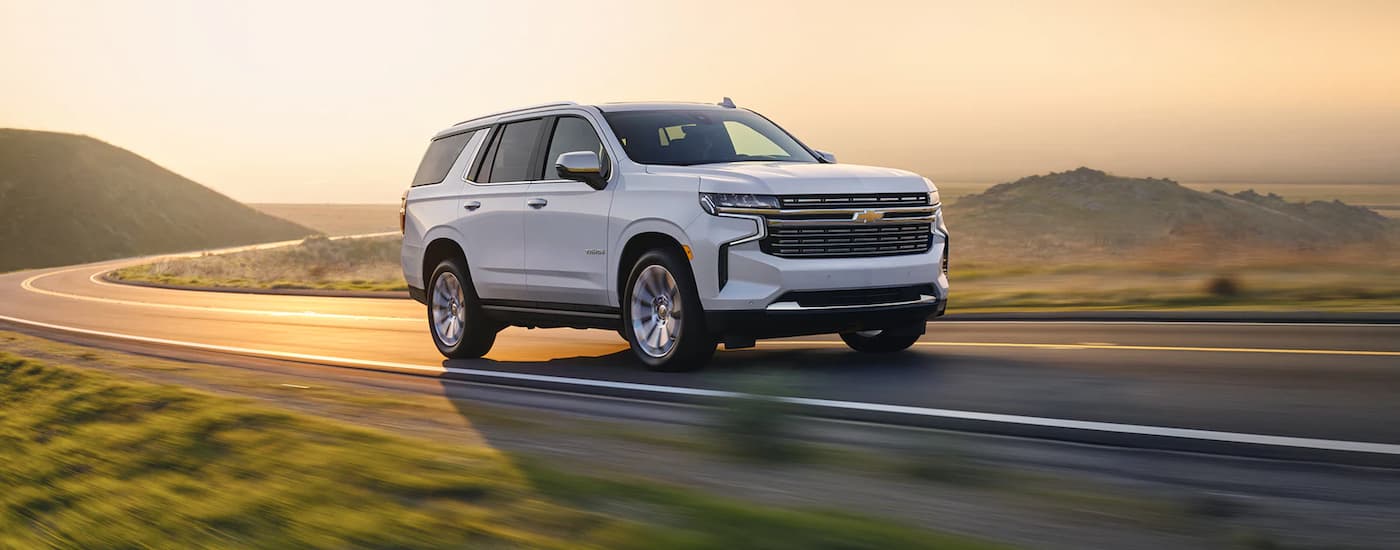 A white 2022 Chevy Tahoe Premier is driving on a winding road after leaving a Chevy dealer near New Iberia.