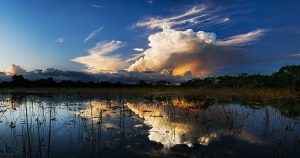 a moorland at sunset with a large cloud in the sky