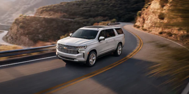 a silver 2021 Chevrolet Suburban driving on a winding road