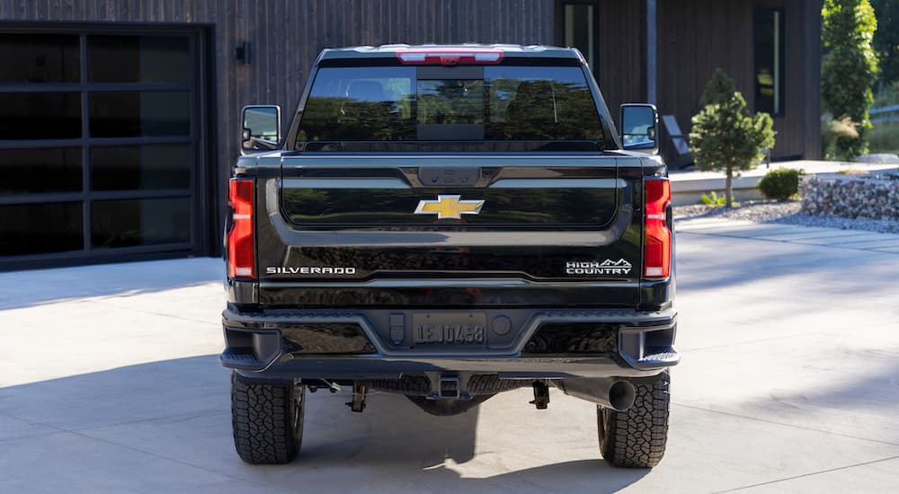 A black 2024 Chevy Silverado 2500 HD High Country is shown from the rear after leaving a dealer that has a Chevy Silverado HD for sale.