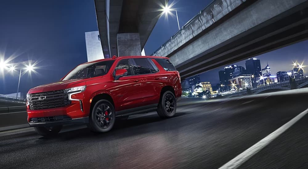A red 2024 Chevy Tahoe RST driving under a bridge after visiting a Chevy dealer near Baton Rouge.