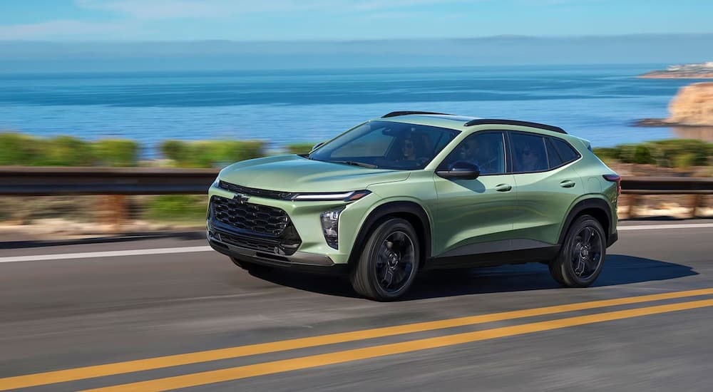 A green 2024 Chevy Trax angled left and driving down a road.