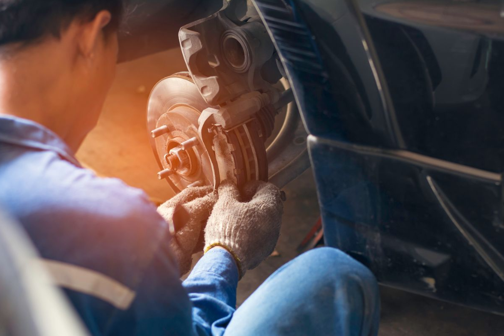 a mechanic working on the brakes for a vehicle.