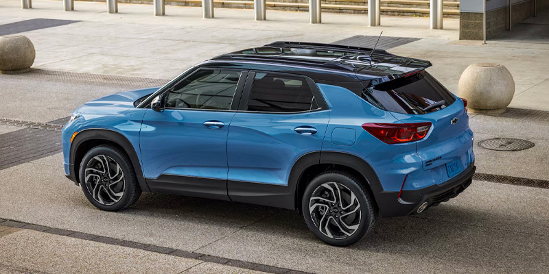 Gray 2026 Chevrolet Trailblazer SUV parked outdoors in Lafayette, LA, partially obscured by overlay text, with a glimpse of its roofline and surrounding greenery in the background.