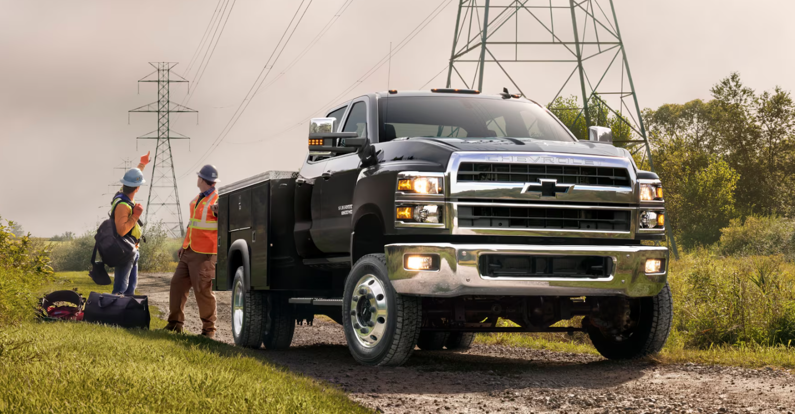Red Silverado HD parked outside a construction site with a bridge and water in the background