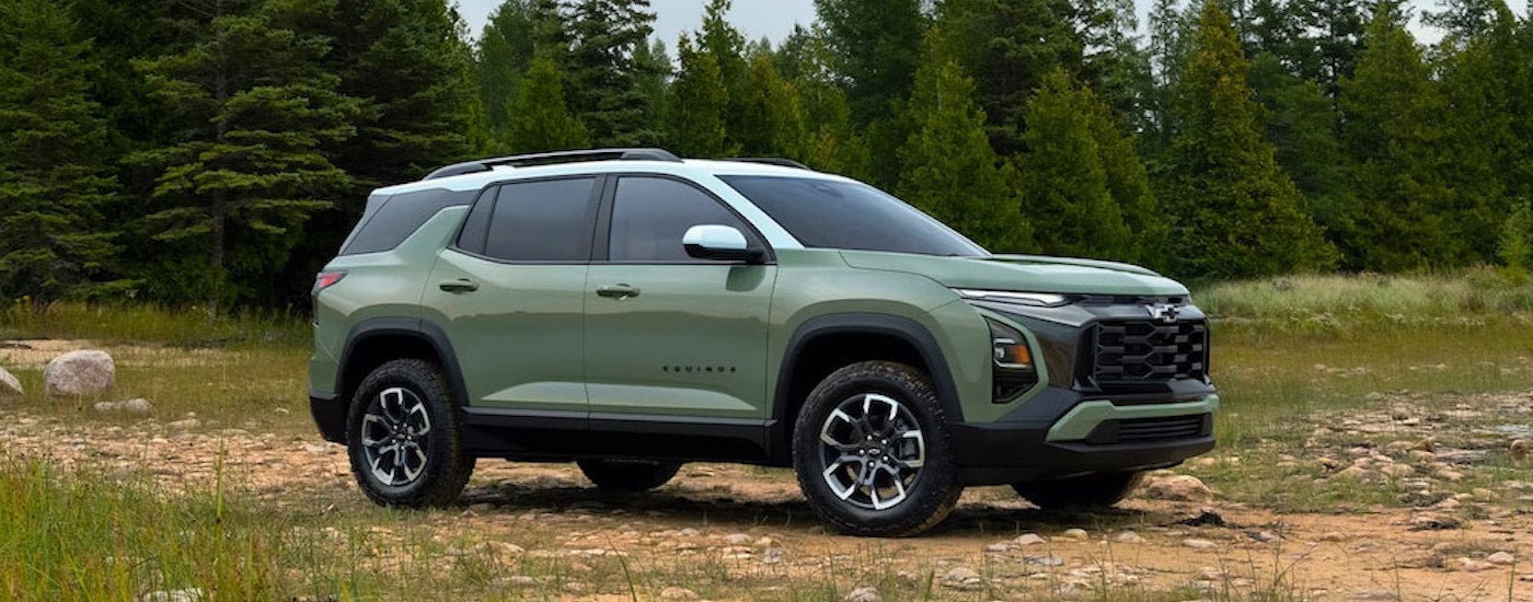 A green 2025 Chevy Equinox ACTIV is shown from the side while parked off-road.